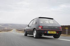 a black car driving down the road with mountains in the background