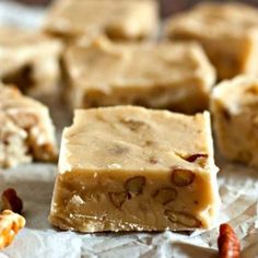 pieces of peanut butter fudge on top of wax paper with nuts scattered around it