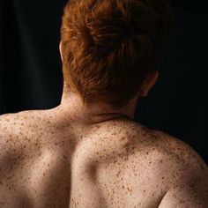 the back of a man with freckles on his body and chest is shown