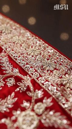 red and gold brocaded fabric with white flowers on the border, close up