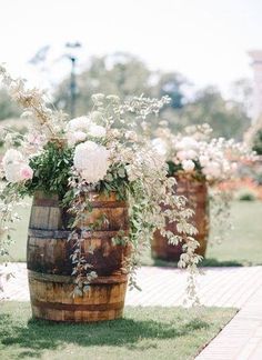 three wooden barrels with flowers in them on the grass