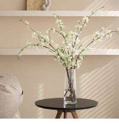 a vase filled with white flowers sitting on top of a table next to a chair