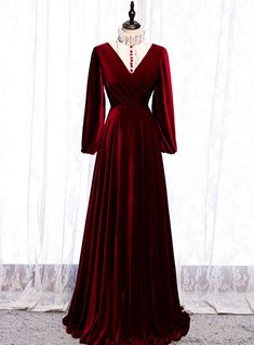 This dress is a mix of Victorian and modern. The burgundy dress has a white ruffled high neck that gives it a Victorian look, the neckline is further bedecked with red buttons that complement the white base of the dress. Long velvet sleeves have a style statement making look. The deign of the dress is such that it accentuates the curvatures of your figure and make it look even more beautiful. The skirt extends from the waistline to the floor. The whole dress is a sight to behold and mesmerizes the onlookers. The back of the dress has a v plunge and a zip at the back that completes the look of the dress. High Neck Long Sleeve Prom Dress, डिजाइनर कपड़े, Fancy Fashion, Simple Bridesmaid Dresses, Dream Prom, V Neck Prom Dresses, Red Velvet Dress, Long Sleeve Prom, Burgundy Bridesmaid Dresses