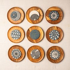 nine wooden plates with designs on them sitting on a table