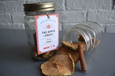 an apple crate next to a glass jar with cinnamon sticks in it and a tag on the lid