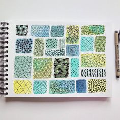 an open notebook with various designs on it and a pen next to the book cover