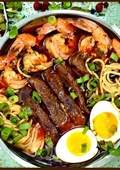 a large bowl filled with meat, noodles and veggies next to an egg