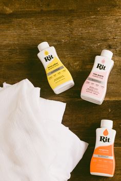 three different types of hand sanitizers sitting on top of a wooden table next to white napkins