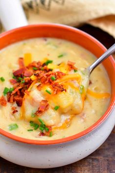 a close up of a bowl of soup with cheese and bacon on top, with a spoon in it