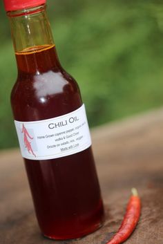 a bottle of chili oil sitting on top of a wooden table next to a red pepper