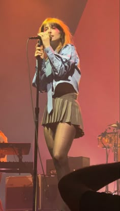 a woman standing on top of a stage holding a microphone in her hand and singing