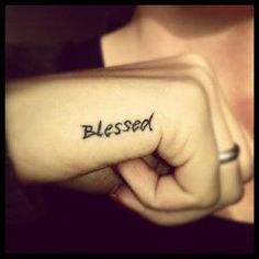 a woman holding her hand up to the camera with an inked word on it