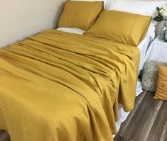 a bed with yellow sheets and pillows on top of it next to a white wall