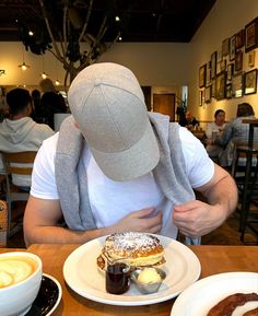 a man with a hat on his head sitting at a table in front of food