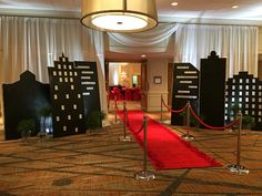 a red carpeted area with black and white buildings on either side, and a red carpet leading up to the entrance