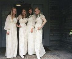 four women in white dresses posing for a photo