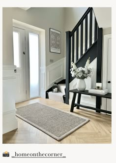 a white and black staircase in a home with flowers on the table next to it