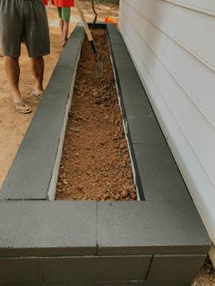 a man standing next to a building with a shovel in it