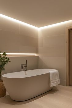 a large white bath tub sitting next to a plant