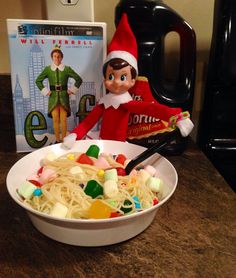 an elf is sitting in front of a bowl of noodles with candy on the side