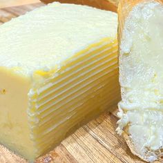 a piece of cheese sitting on top of a cutting board next to a loaf of bread