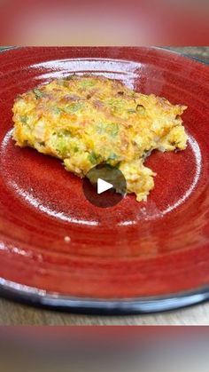 a red plate topped with an omelet on top of a wooden table