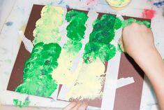 a child is painting green and yellow trees