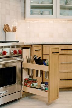 an open drawer in the middle of a kitchen with spices and utensils on it