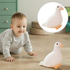 a baby laying on the floor next to a white duck