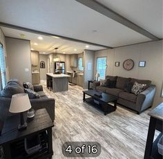 a living room filled with furniture and a large kitchen in the backround behind it