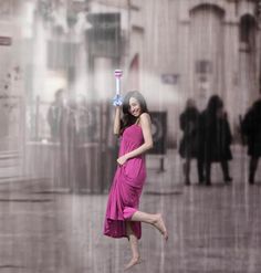 a woman in a pink dress holding an electric hair dryer over her head while walking through the rain