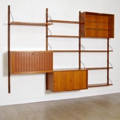 an empty room with a wooden shelf and shelving unit on the wall next to it