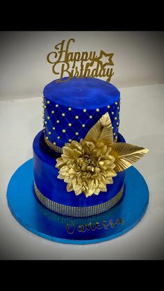 a blue and gold birthday cake with a flower on top