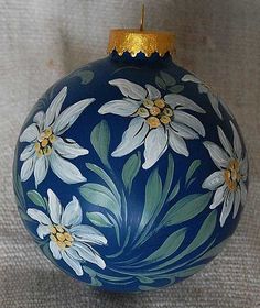 a blue ornament with white flowers painted on it's sides and gold trim