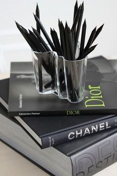 three books stacked on top of each other with pencils in glasses next to them