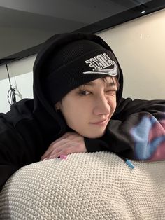 a young man wearing a black nike beanie laying on top of a white couch