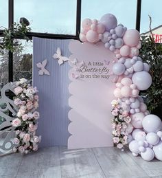 there is a large balloon arch with flowers and butterflies on it