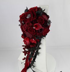 a white cake with red roses and black ribbons on it's side, sitting on top of a table