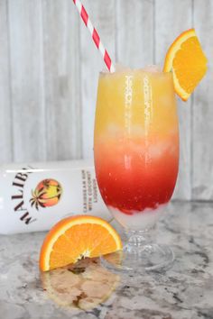 an orange and red drink sitting on top of a table next to a carton of coconut