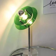 a green table lamp sitting on top of a glass shelf next to a white wall