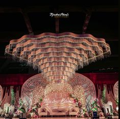 an elaborately decorated stage with chandeliers and flowers on the ceiling is lit up at night