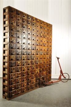 a bike is parked next to a large wooden box that has many drawers on it