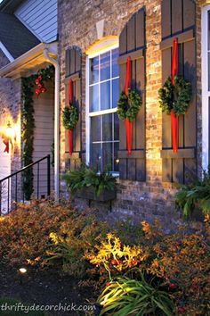 christmas wreaths are hung on the windows of this house