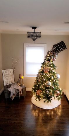 a decorated christmas tree in the corner of a room next to a window with lights on it