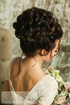 a woman in a white dress holding a bouquet of flowers and looking at the back of her head