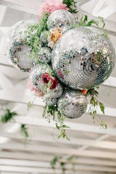 disco balls hanging from the ceiling with flowers and greenery