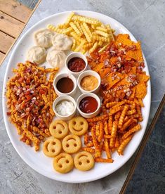 a white plate topped with different types of food next to dipping sauces and fries