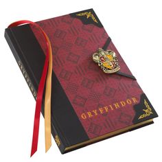 a harry potter notebook with a hogwarts pin on the front and red cover