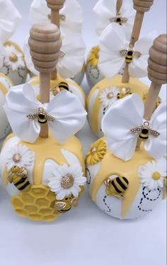 some yellow and white decorated apples with wooden sticks in the middle one has a bee on it