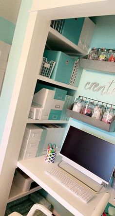 a laptop computer sitting on top of a white desk next to shelves filled with craft supplies